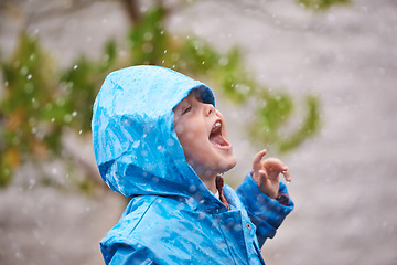 Image showing Boy, jacket and rain in winter with playing for fun, carefree childhood and happiness with freedom. Child, excited and smile with mouth open in nature for vacation, weekend or holiday in cold weather