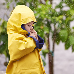 Image showing Boy, nature and standing with jacket in rain for thinking, cold and sad on winter day in Australia. Young kid, childhood and development with pondering for gloomy, wet and lonely in rainy weather