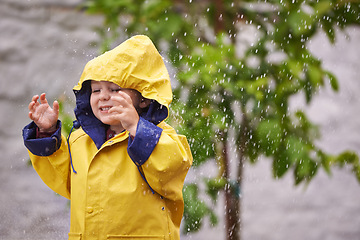 Image showing Boy, jacket and rain with smile in winter for playful, carefree childhood and freedom in Australia. Happy, little kid and water in nature for holiday, vacation or travel on weekend in cold weather