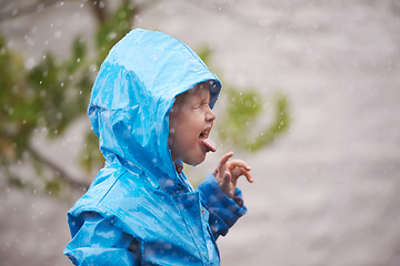Image showing Boy, rain jacket and playing in winter with happiness, fun and carefree childhood in cold weather. Young child, tongue out and water in nature for vacation, holiday and weekend enjoyment in Australia