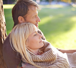 Image showing Couple, park and relax by tree in embrace, romance and bonding for love at park on weekend trip. People, care and outdoor date for relationship or marriage, support and hug in nature for commitment