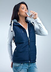 Image showing Woman, drinking water for health and hydration in studio, nutrition and wellness with thirst on grey background. Liquid, aqua and mineral with h2o in glass, fresh and clean for refreshment and detox