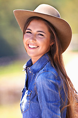 Image showing Happy woman, portrait and cowgirl with hat on farmland for adventure, travel or outdoor journey in Texas. Female person with smile in western fashion, denim shirt and cap at ranch in the countryside