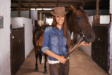 Image showing Cowgirl, portrait and happy woman with horse at barn or stable in Texas for recreation. Western hat, person and animal at ranch with pet, livestock or stallion for hobby with care at equestrian farm