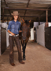 Image showing Cowgirl, portrait and happy woman with horse at farm or barn in Texas for recreation. Western hat, animal and person at ranch with pet, livestock or stallion for hobby with care at equestrian stable
