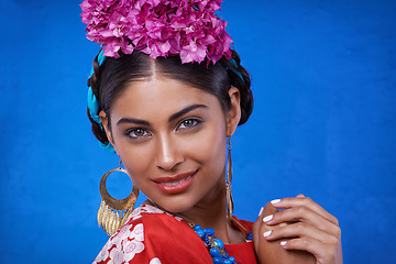 Image showing Portrait, beauty and happy woman with flowers in hair isolated on blue studio background in India. Face, smile or person with floral cosmetics, natural or organic makeup on skin with leaf for fashion