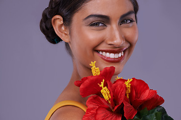 Image showing Portrait, smile and woman with flowers for makeup, skincare or health isolated on a purple studio background in India. Face, person and cosmetics with bouquet for natural beauty with organic hibiscus