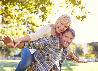 Image showing Couple, portrait and happy for park piggyback with love together on vacation or nature explore, sunshine or relax. Man, woman and face for holiday in environment for relationship date, summer or trip