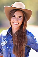 Image showing Happy woman, portrait and cowgirl with hat for nature adventure, travel or outdoor journey in Texas. Young female person with smile in western fashion, denim shirt and cap at ranch in the countryside