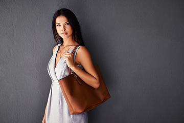 Image showing Studio, portrait and handbag with fashion, proud and accessories with cool and dress. Woman, face and model with confidence, beauty and happiness with purse and style isolated on gray wall background