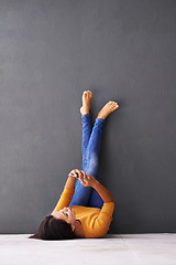 Image showing Woman, phone and wall background, floor and social media while relaxing on tech with fashion. Female person, beauty and chill at home for scroll, internet and wellness in jeans with feet for rest