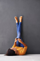 Image showing Wall, feet up or woman with phone relax on floor with social media, scroll or web communication on grey background. Smartphone, search or lady person on ground with google it, app or Netflix sign up