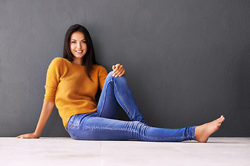 Image showing Portrait, woman and relax or style on floor with casual outfit for fashion or comfort, leisure and wellness with smile. Female person, isolated with grey background or wall for clothing with mockup