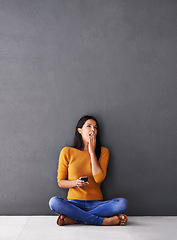 Image showing Bored, tired or woman with phone yawn on floor for social media, scroll or web search on wall background. Fatigue, burnout or female person with smartphone app on the ground sleepy from reading ebook