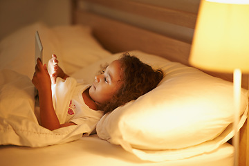 Image showing Girl, child and tablet in bed at night, comfortable and online for games or playing in home. Female person, kid and resting in bedroom or lying to relax, website and internet or app for entertainment