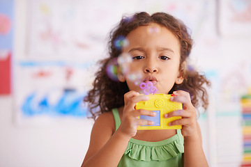 Image showing Preschool, toy and girl playing with bubbles for growth and development of child with game. Kindergarten, soap and wand with cute kid for fun in classroom with drawings by youth in background