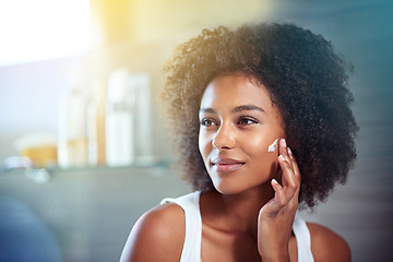 Image showing African woman, beauty and facial cream with smile, wellness or afro in home bathroom for morning routine. Girl, person and serum with cosmetics, skincare or transformation with self care in apartment