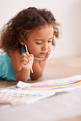 Image showing Young girl, painting and brush on floor with paper, creativity and drawing for learning or childhood. Toddler, motor skills and growth for development child enjoying, hobby or playing at home