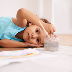 Image showing Children, portrait and girl on a floor for painting, art or playing in her home with rainbow, paper or fun. Face, paintbrush or kid on the ground with water for for color splash, creative or drawing