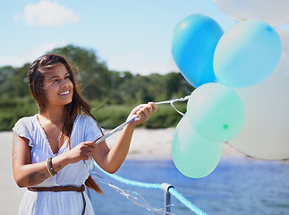 Image showing Woman, happy and hold balloons on beach for freedom on holiday season or travel, relax and carefree with joy. Female person, outdoors and helium for celebration or birthday on summer vacation.