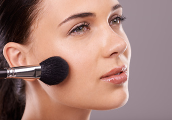 Image showing Woman, beauty and brush with makeup, thinking and studio for glamour, radiance and lip gloss. Female person, blush brush and foundation in grey background, vision and attractive confidence cosmetics