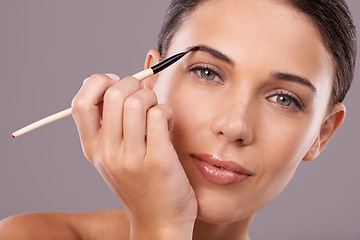 Image showing Woman, beauty and eyebrow brush with makeup, portrait and studio for glamour and radiance and lip gloss. Female person, blush and foundation in grey background, sexy and attractive confidence