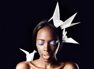 Image showing Black woman, eyeshadow and fine art with beauty, dove or origami birds on a dark studio background. Closeup or face of African female person or model with blue makeup or cosmetics on mockup space