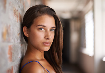 Image showing Portrait, serious and woman by brick for confidence or casual fashion in corridor alone. Face, skin or young student on wall, girl or hair of female person in hallway for profile picture in Argentina