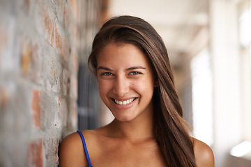 Image showing Portrait, smile and woman by brick wall at school for confidence, education or learning in corridor alone. Face, happy young student and girl in hallway of university for profile picture in Argentina