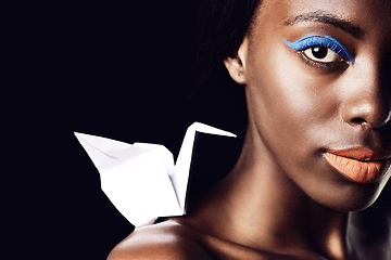 Image showing Black woman, portrait and makeup with cosmetics, fine art and origami bird or dove on a dark studio background. Closeup or face of African female person or model with beauty eye color on mockup space