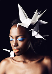 Image showing Black woman, fine art and blue eyeshadow with beauty, dove or origami birds on a dark studio background. Closeup or face of African female person or model with makeup or cosmetics on mockup space