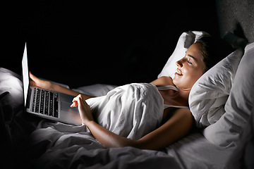 Image showing Bedroom, laptop and night with woman streaming content, video or browsing social media in dark home. Bed, computer and subscription with young person in apartment to relax on weekend time off