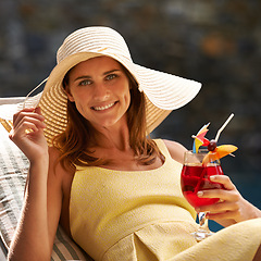 Image showing Woman, cocktail and glass by swimming pool on lounge chair for summer, holiday and tropical vacation. Young person or tourist in portrait by hotel with hat, drink or alcohol for happy, outdoor break