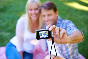 Image showing Camera, screen and couple in a park, date and happiness with love and romance with a selfie in nature. Photograph, outdoor and memory with man and woman with marriage and relationship with sunshine