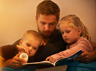 Image showing Night, kids or father reading book in home for learning, education or storytelling in a house for care. Family, relax or dad with children siblings for a fantasy with a girl, boy or support for love