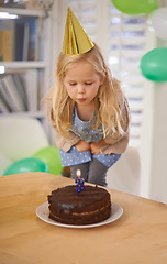 Image showing Child, birthday and blow cake candle in home, celebration for three year old or party wish. Happy girl, dessert on table, excited or cheerful event for growth or special decoration and fun hat
