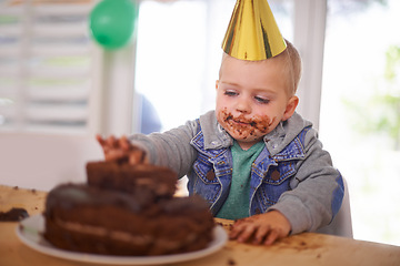 Image showing Baby, birthday and eating cake in home, celebration for infant or party. Happy boy, dessert on table or excited cheerful event for growth with special decoration hat or messy face and childhood fun