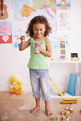 Image showing Playing, kid and blowing bubbles with toys for childhood development, smile and having fun alone. Happiness, growth and face of young girl in kindergarten for learning, soap liquid and games