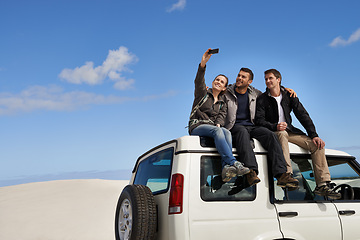Image showing Friends, car and selfie in desert with smartphone with smile for adventure, holiday and road trip to travel. People, happy excited in sand dunes for vacation or break with bonding for memory