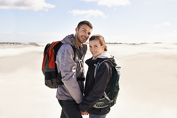 Image showing Hiking, sand dunes and couple in portrait for adventure, desert landscape and travel on holiday. Holding hands, explorers and happy nomad people in Sahara terrain, outdoor or dry climate for love