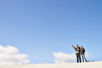 Image showing sand dunes, space and couple hiking for adventure, desert and travel on outdoor holiday for love or view. Sky mockup, explorers trip and nomad people pointing in Sahara terrain, nature or dry climate