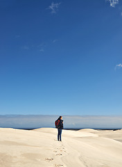 Image showing Hiking, sand dunes and woman in nature for adventure, desert landscape and travel for holiday. Mockup space, explorer and nomad person in Sahara terrain, outdoor and dry climate for view or scenery