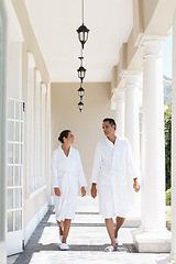 Image showing Holiday, robe and couple at hotel terrace with smile, walk and relax together at wellness spa getaway. Hospitality, happy woman and man at luxury villa for travel, vacation and love on romantic date