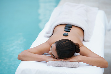 Image showing Relax, hot stone massage and woman at pool at spa for health, zen wellness and luxury holistic treatment. Self care, peace and girl on table for body therapy, comfort and calm pamper service at hotel