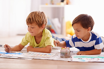 Image showing Young children, painting and creative with paint brush on floor or playing room, hobby and drawing together at home. Brothers, motor skills and growth for childhood development with smile for artwork