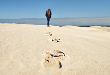 Image showing Person, hiking and walking on sand dunes for fitness adventure in desert and extreme sport in arid climate. Athlete, back or survival gear for nature exploration, footprints or wanderlust vacation