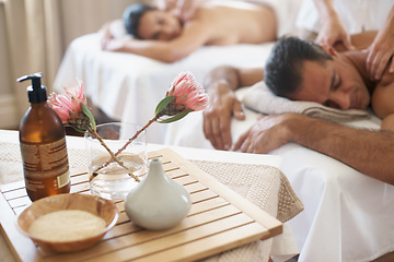 Image showing Hotel, flowers and couple in spa to relax on bed or break with luxury pamper treatment tools on table. Protea, facial oil or woman with man at resort or salon for natural healing benefits or massage