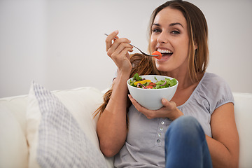 Image showing Portrait, happy woman and eating a salad on couch, lunch and healthy food for nutrition in home. Smile, face and young lady with vegetables on sofa, vitamins and detox or weight loss in living room