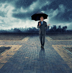 Image showing Businessman, umbrella and walking for security in rain, insurance at crossroads by city background for choice. Mature person, winter and street with dark clouds in storm and future decision for path