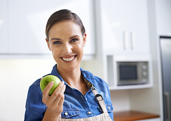 Image showing Happy woman, portrait and kitchen with apple for diet, natural nutrition or healthy eating at home. Face of female person with smile and organic green fruit for vitamins, fiber or health and wellness